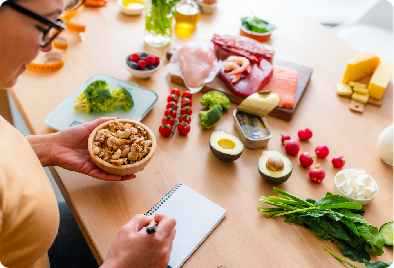 Writing in notebook surrounded by healthy foods