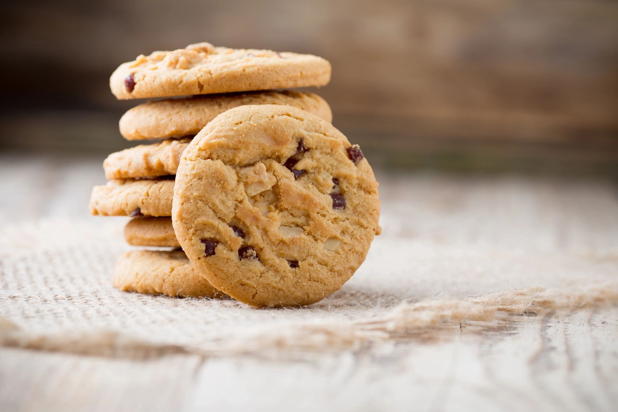 Stack of chocolate chip cookies on a rustic surface.